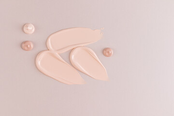 Three chic samples of foundation powder in a classic tone on a beige background. drops of foundation. texture samples for product advertising.