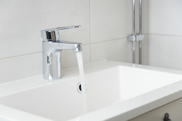 Modern bathroom faucet, water tap with running water and white sink, pure water concept, saving natural recourses concept banner with copy space