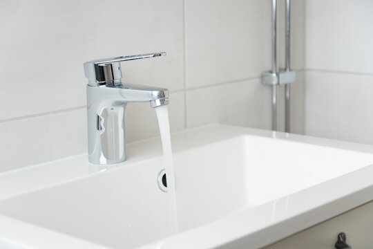 Modern bathroom faucet, water tap with running water and white sink, pure water concept, saving natural recourses concept banner with copy space