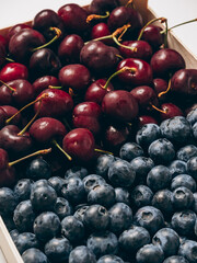 A tray with mix of fresh ripe sweet cherry and blueberries background closeup