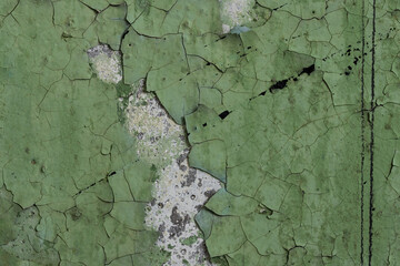 Green peeling paint on the wall. Old concrete wall with cracked flaking paint. Weathered rough...