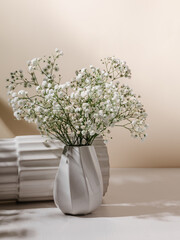 White ceramic vase with gypsophila flowers and sunlight shadows, beautiful vase composition. Aesthetic still life, luxury home decoration, beautiful interior for design, poster or print
