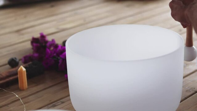 Hand playing a quartz crystal singing bowl for sound therapy