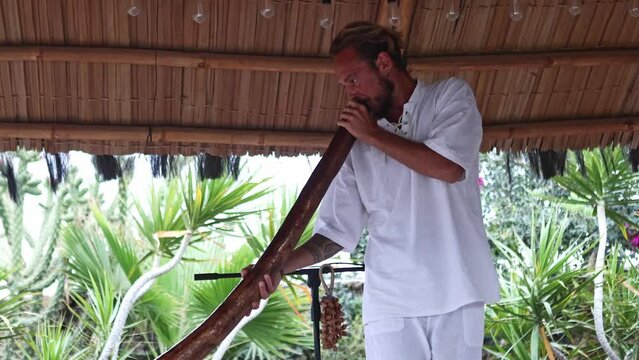 Man playing a didgeridoo in a therapeutic sound session