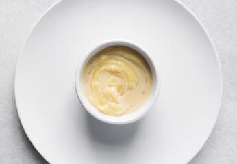 Overhead view of nigerian akamu with milk, pap akamu or ogi in a white bowl with evaporated milk, top view of nigerian corn pudding in a white ramekin