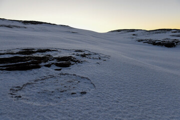 Landscape shot highlighting the rugged mountains and snow-covered beaches of arctic norway during a brief golden hour during the long winters.