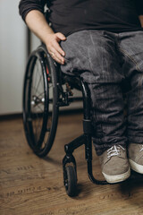 Obraz premium Young man with disability looking through window while sitting on wheelchair in room
