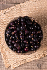Black currant in a bowl on wooden background. Organic berries. 