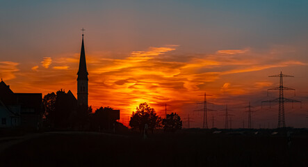 Obraz premium Sunset with a church silhouette near Wallerdorf, Künzing, Deggendorf, Bavaria, Germany