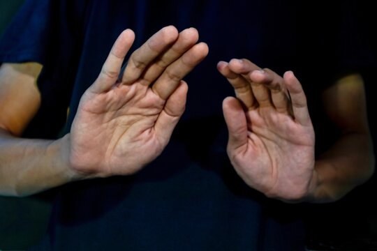 Man give signs of fear and rejection on dark background. Gesturing Stop or rejecting something.