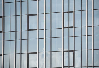 empty glass windows of a modern building with a reflection of the sky in the glass