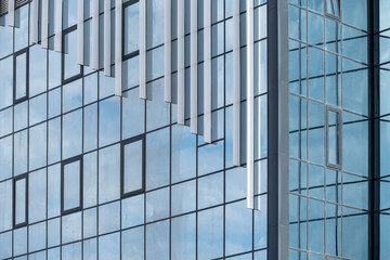 empty glass windows of a modern building with a reflection of the sky in the glass