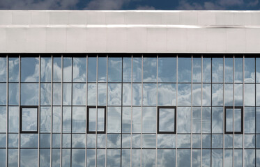 Fototapeta premium empty glass windows of a modern building with a reflection of the sky in the glass