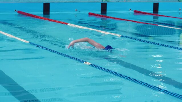 A young beautiful woman goes in for sports, enjoys swimming, crawl style in a swimming pool. Body training in water, fitness, self-care, preparation for the summer season.