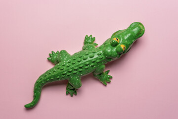 Green crocodile toy on pastel pink background. Minimal art concept.