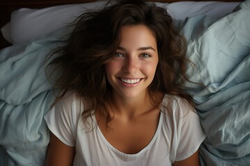 Top view of beautiful young woman lying on bed and smiling