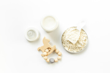 Feeding time for baby. Milk in bottle with toy on white background, top view