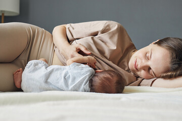 Home lactation support. Home breastfeeding routine. Caucasian beautiful mother breastfeeding her...
