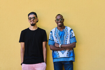Two Male Friends: African American Teenager in Sudanese Traditional Attire Leaning Against Yellow...