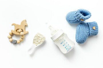 Feeding time for baby. Milk in bottle with toy on white background, top view