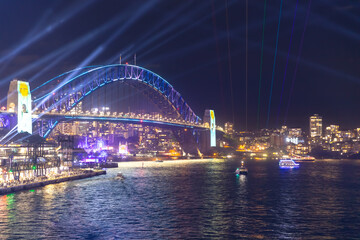 Colourful Light show at night on Sydney Harbour NSW Australia. The bridge illuminated with lasers and neon coloured lights  Vivid Sydney Laser and Light Drone show