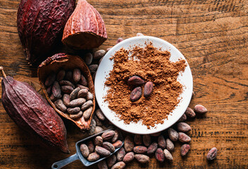 Top view of Natural cocoa powder with brown cocoa beans and dry cacao pod  on a vintage wooden table.