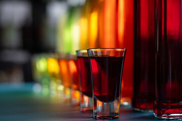 Glasses and bottles with berry alcoholic tincture or homemade wine on table