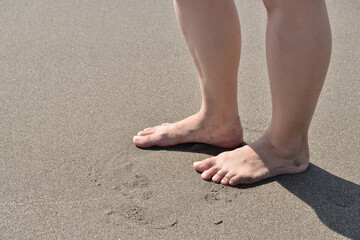 砂浜に立つ若い女性の足