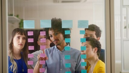 Thoughtful african american man planning business future, checking sticky notes in office workspace.  