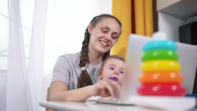 Mom works and looks after the child. happy childhood dream concept for a little child. young mother works remotely via lifestyle laptop during quarantine and looks after her small child