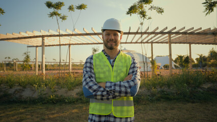 Portrait successful confident smiling Caucasian man male businessman ecological engineer agronomist hardhat uniform crossed hands looking camera outside construction. Agriculture eco farming business