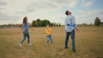 Happy Caucasian family woman mother female man male father little child son kid playing plane toy airplane flight having fun play running field outside village meadow field. Parenting active childhood