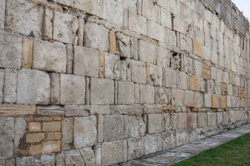 The fortress wall. A monument of ancient Persian fortification architecture. The wall is made of large stone blocks. There are benches for people to rest near the fortress wall.