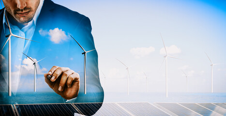 Double exposure graphic of business people working over wind turbine farm and green renewable...