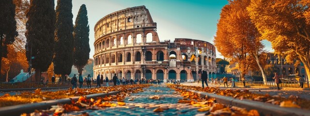 A large Roman colosseum is surrounded by trees and people. The leaves on the ground create a beautiful autumn scene - Powered by Adobe