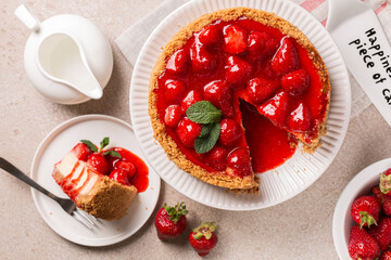 Classic baked Cheesecake  with a strawberry topping sauce directly above. Cake server where is...