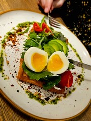 Delicious Belgian waffles with egg, with microgreens, avocado and vegetables in a plate, close-up. Delicious sandwich with egg. Ketogenic diet breakfast