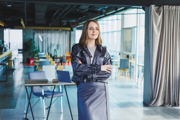 A woman in a leather jacket is standing in a cafe. Beautiful girl in casual clothes.