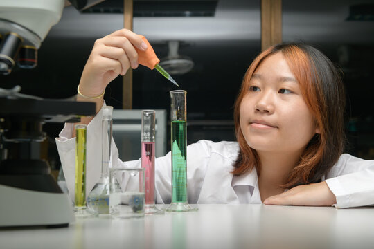 girl scientist loads liquid sample into test tube with plastic pipette. education and science