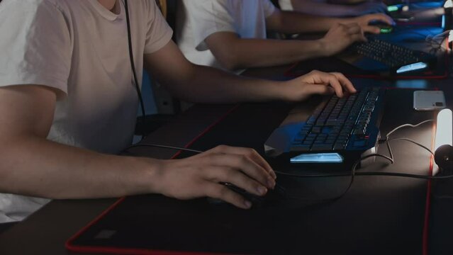Gamers play video game on PC at computer club, professional E-sport tournament Cyber sport championship. Gaming mouse RGB lighting keyboard on mat close up. Multiplayer first-person shooter strategy