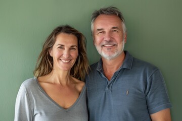 Obraz premium Portrait of a grinning couple in their 40s donning a classy polo shirt isolated in soft green background
