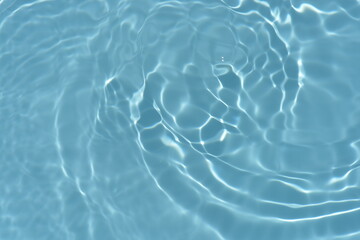 Blue water with ripples on the surface. Defocus blurred transparent blue colored clear calm water surface texture with splashes and bubbles. Water waves with shining pattern texture background.