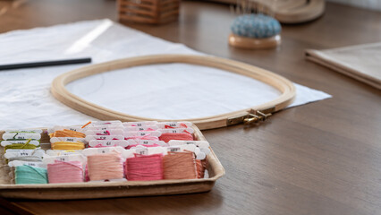 Bobbing of Thread for Embroidery on a Wooden Table with Hoop and Fabrics