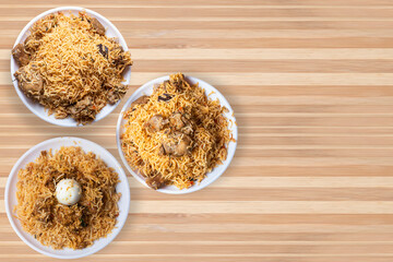 Indian famous biryani dishes on white plate. Chicken biryani, mutton biryani, egg biryani on wooden table.