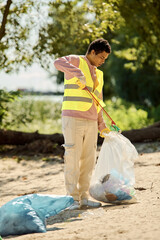 A man stands along the shoreline, holding a plastic bag, contemplating the environmental impact of...