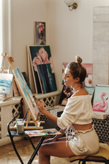 Young female artist is painting on a canvas in an art studio