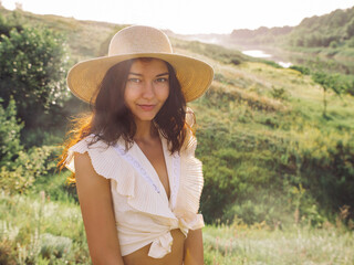 Smiling Woman in Straw Hat Enjoying Sunny Day in Scenic Countryside