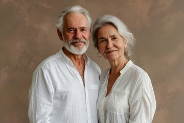 Portrait of a satisfied couple in their 70s wearing a classic white shirt over soft brown background