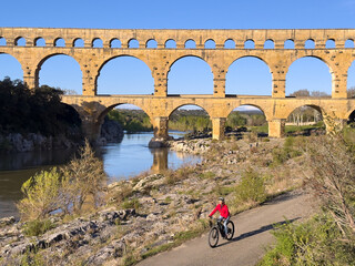senior woman mountainbiking with her e bike below the famous roman aqueduct of Pont du Gard near...