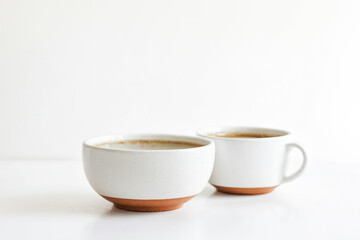 Two white ceramic mugs with brown rim on white background